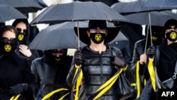 身穿黑衣戴着核辐射图样口罩的人们在明斯克纪念35年前在切尔诺贝利核事故中的死难者。（2021年4月26日）