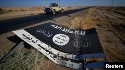 A black sign belonging to Islamic State militants is seen on the road in Al-Al-Fateha military airport south of Hawija, Iraq, Oct. 2, 2017.