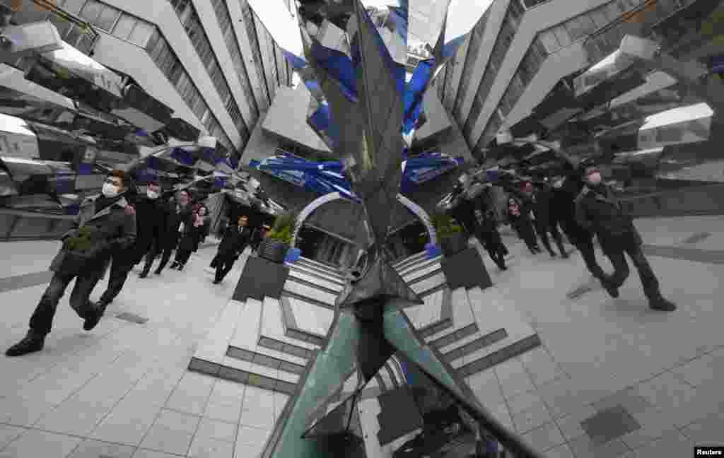 Passers-by are reflected on a decoration at the entrance of a train station in Tokyo, Japan, Feb. 20, 2013. 