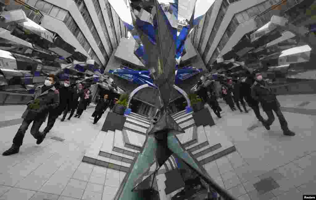 Passers-by are reflected on a decoration at the entrance of a train station in Tokyo, Japan, Feb. 20, 2013.