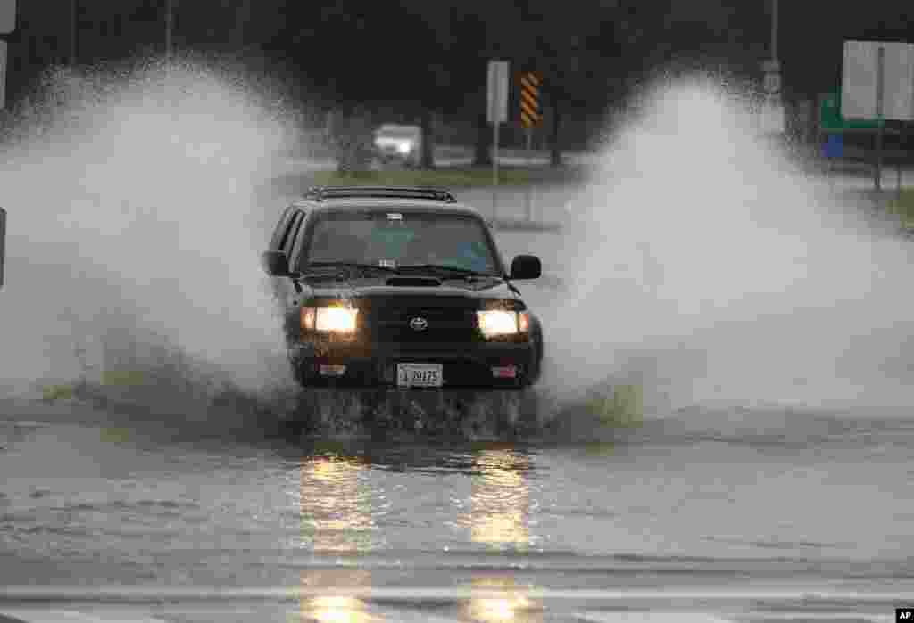 A car plows through a flooded street in the Ocean View area in Norfolk, VA., Sunday, Oct. 28, 2012.