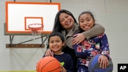  Lara Mae Chollette, a coach of youth soccer and basketball, poses for a photo with her son Jaylen, 7, left, and daughter Linda, 10, at a community gym in Seattle.