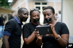 FILE - Journalists with tape on their mouths gather on the occasion of World Press Freedom Day, Bujumbura, Burundi, May 3, 2015.