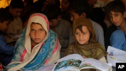 FILE - Pakistani children study in a makeshift school after fleeing from the neighboring Khyber tribal region due to fighting between security forces and militants, in Peshawar, Pakistan.
