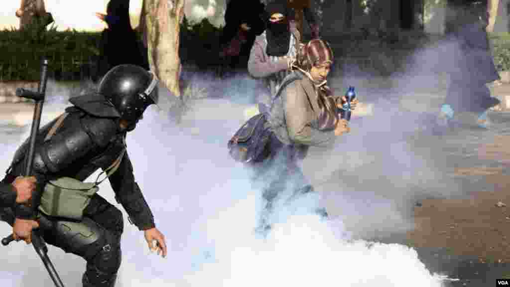 Women and police dodge tear gas during a protest at Al-Azhar University in Cairo, Dec. 11, 2013. (Hamada Elrasam for VOA)