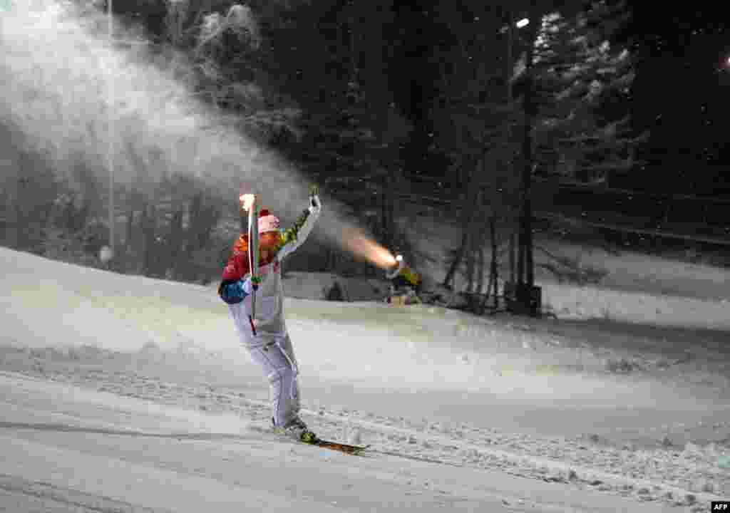 Photo released by the Sochi 2014 Winter Olympics Organizing Committee shows a torchbearer skiing with his torch at a ski resort near the Siberian city of Krasnoya, some 3500 km (2174 miles) east of Moscow, Russia.