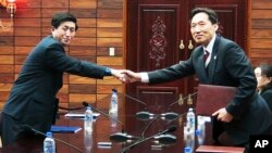Kepala delegasi tingkat kerja Korea Selatan Lee Duk-haeng (kanan) berjabat tangan dengan mitranya dari Korea Utara, Park Yong Il seusai bertukar dokumen perjanjian yang telah ditandatangani di Tongilgak, wilayah perbatasan Panmunjom, Korea Utara (5/2).