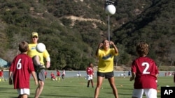 Sydney Leroux del Equipo Nacional Femenino de Fútbol de EE.UU. y la exjugadora Alexi Lalas, enseñan a niños a jugar el deporte en una reciente clínica deportiva patrocinada por Nesquik. El equipo estadounidense ganó la Copa Mundial de Fútbol Femenino 2015. 