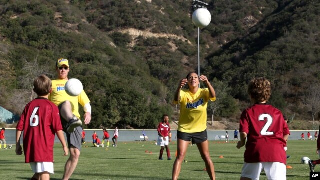 Sydney Leroux del Equipo Nacional Femenino de Fútbol de EE.UU. y la exjugadora Alexi Lalas, enseñan a niños a jugar el deporte en una reciente clínica deportiva patrocinada por Nesquik. El equipo estadounidense ganó la Copa Mundial de Fútbol Femenino 2015. 