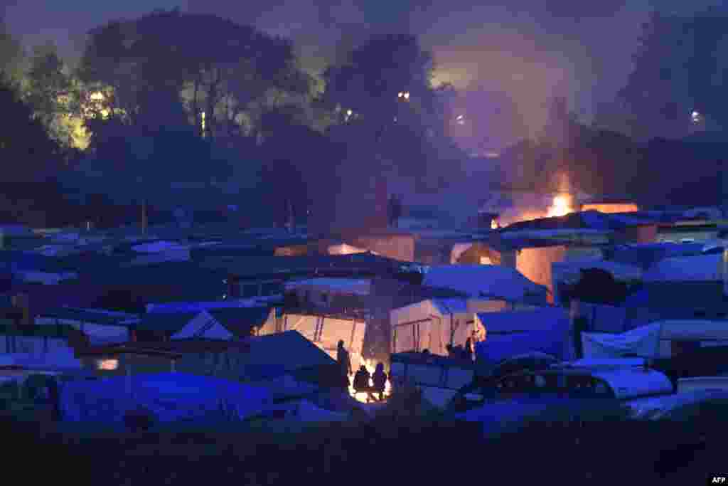 Migrants gather around a bonfire to warm up in the &quot;Jungle&quot; migrant camp in Calais, northern France, at sunset during the full evacuation of the camp, in Calais, northern France.