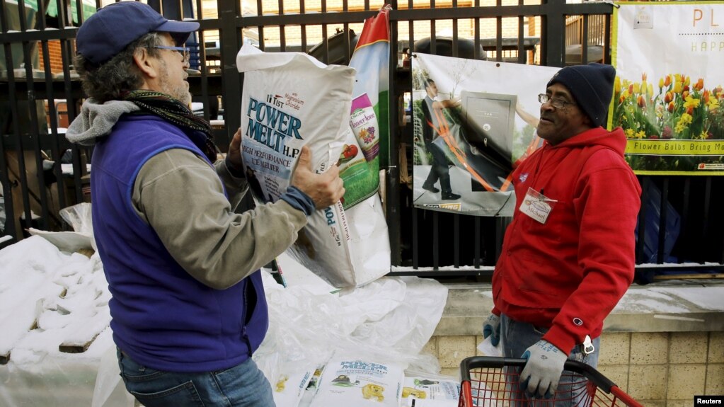 FILE - Employee Michael Torney (R) watches a customer carry out a bag of ice melt at Strosniders Hardware store in Silver Spring, Maryland, Jan. 21, 2016.