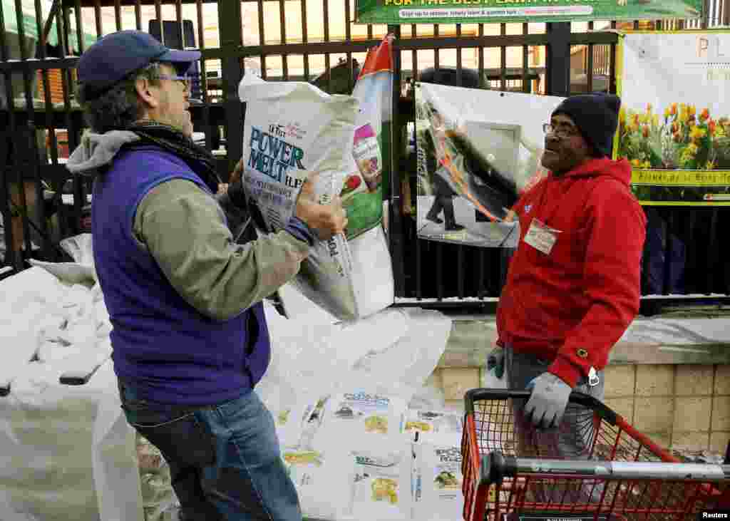 Employee Michael Torney (R) watches a customer carry out a bag of ice melt at Strosniders Hardware store in Silver Spring, Maryland, Jan. 21, 2016.
