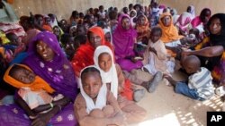 Women and children wait to participate in a vaccination campaign against meningitis at the community center in Al Neem camp for Internally Displaced People in El Daein, East Darfur, Sudan, October 8, 2012.