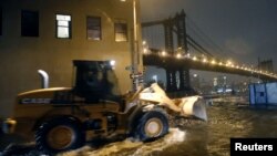 Un vehículo de la construcción intenta contener el agua en Brooklyn, New York. 
