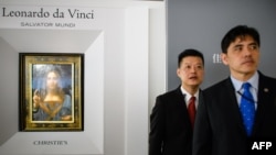 2017年10月13日，被香港媒体认定为前美国中央情报局特工李振成（音译）的男子（打蓝色领带者）站在佳士得香港展厅的保安员前面，身后是达芬奇的画作。