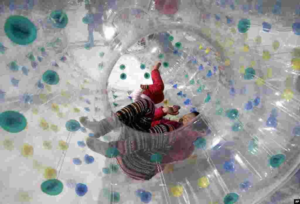 Children play inside an inflatable tube on the snow at Taoranting Park&#39;s temple fair for Lunar New Year celebrations in Beijing, China.