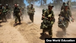 Israeli soldiers walk towards a staging area outside the Gaza Strip, July 18, 2014.