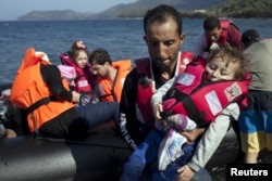 Người tị nạn Syria bế con lên bờ sau sau khi đến đảo Lesbos của Hy Lạp trên một chiếc thuyền cao su, ngày 11/9/2015.