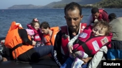 A Syrian refugee holds a baby moments after arriving on a dinghy on the Greek island of Lesbos, Sept. 11, 2015. 