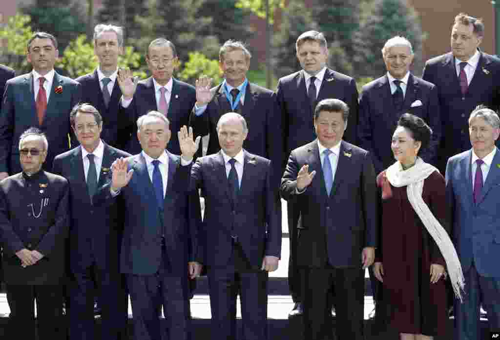 Russian President Vladimir Putin, foreground center, and foreign dignitaries pose for a photo after the Victory Parade marking the 70th anniversary of the defeat of the Nazis in World War II, at the Tomb of Unknown soldier, outside Kremlin wall, in Moscow