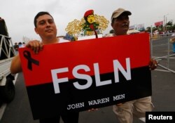 Supporters of Nicaragua's President Daniel Ortega hold a flag of the Sandinista National Liberation Front in a march in Managua, July 23, 2018.