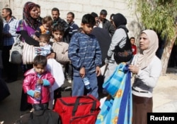 FILE - Syrian families leave the besieged town of Moadamiyeh, a Damascus suburb, Oct. 29, 2013.