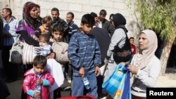 FILE - Syrian families leave the besieged town of Moadamiyeh, a Damascus suburb, Oct. 29, 2013.