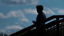 A pedestrian uses his phone in Kilbourn Reservoir Park Wednesday, Sept. 8, 2021, in Milwaukee. (AP Photo/Morry Gash)