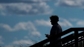 A pedestrian uses his phone in Kilbourn Reservoir Park Wednesday, Sept. 8, 2021, in Milwaukee. (AP Photo/Morry Gash)
