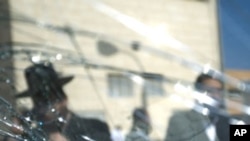 Orthodox Jewish men are seen through a shattered window near a synagogue after a rocket was fired by Palestinians militants from Gaza Strip hit Ashdod, Israel, August 19, 2011