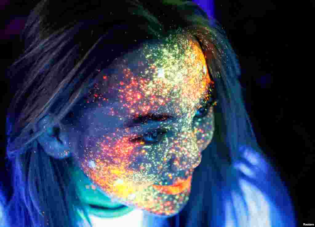 A participant with her face decorated with fluorescent paint smiles before the YARKOcross Night Edition color run race in Almaty, Kazakhstan, Sept. 15, 2018.