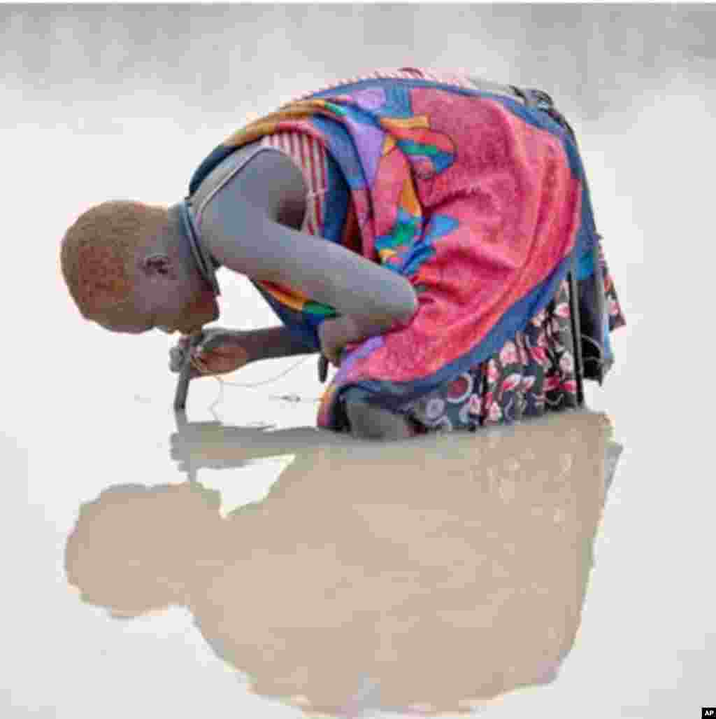 A young herder in Kuse Dam in Terekeka county, north of Juba,&nbsp; uses a pipe filter provided by The Carter Center to strain out infective Guinea worm larvae from water while drinking.