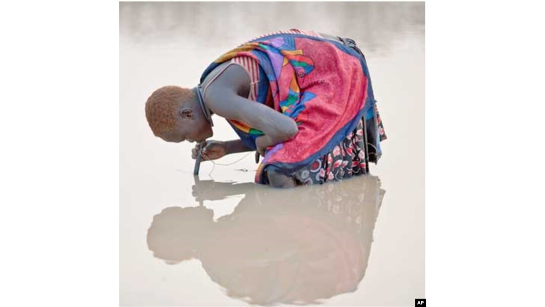 Feb. 6, 2010. Kuse Dam, Terekeka County, Southern Sudan. A young herder in Kuse Dam uses a pipe filter provided by The Carter Center to strain out infective Guinea worm larvae from the water while drinking.