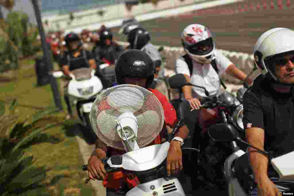 Workers wait in line with their motorcycles and scooters to enter Spain at its border with the British territory of Gibraltar, south of Spain.