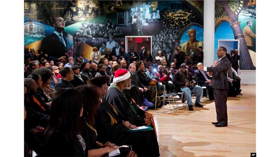 A mural depicting the lives of Malcolm X and his family is the backdrop for artist Jamel Hudson as he sings at a ceremony held on the 50th anniversary of the civil rights leader's slaying in New York's Harlem section, Saturday, Feb. 21, 2015.