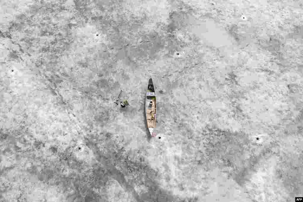 This aerial photo shows a canoe lying on ice, near holes cut by fishermen, on the melting but-still-frozen sea, off Bjoerkoe, Raipaluoto island, Finland.