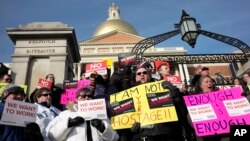 Internal Revenue Service employees Brian Lanouette, of Merrimack, N.H., center right, and Mary Maldonado, of Dracut, Mass., right, join with others as they display placards during a rally by federal employees and supporters, Jan. 17, 2019, in front of the