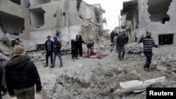 FILE - Residents inspect a crater at a site hit by what activists said were three consecutive air strikes carried out by the Russian air force, the last which hit an ambulance, in the rebel-controlled area of Maaret al-Numan town in Idlib province, Syria, Jan. 12, 2016. 