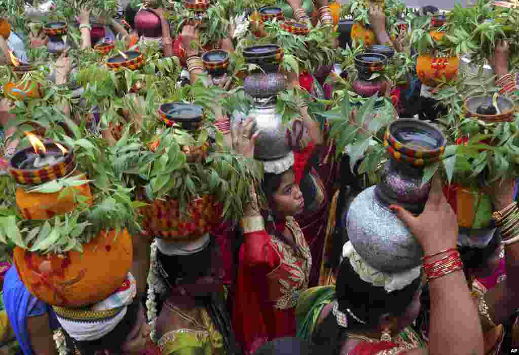 Indian women carry pots filled with cooked rice decorated with turmeric and neem leaves on their heads during the &#39;Bonalu&#39; festival, a ritual offering to the Hindu goddess Kali, in Hyderabad, India. Bonalu is a month-long Hindu folk festival of the Telangana region dedicated to Kali, the Hindu goddess of destruction.
