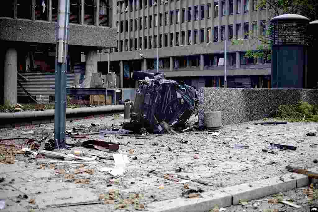 The wreckage of a car lies outside government buildings in the center of Oslo, Friday July 22, 2011, following an explosion that tore open several buildings including the prime minister's office, shattering windows and covering the street with documents.
