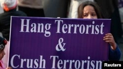 A supporter of political party Pakistan Awami Tehreek (PAT), holds a sign with others condemning an attack by Taliban gunmen on the Army Public School in Peshawar, during a rally in Lahore, Dec. 21, 2014. 