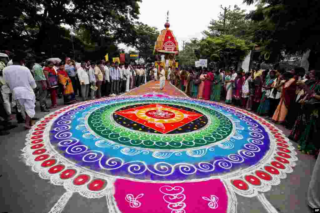 Hindu devotees stand around a traditional artwork made of colored powder during the annual Rath Yatra festival or chariot procession in Hyderabad, India.
