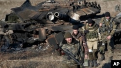 Pro-Russia separatists walk after inspecting a destroyed Ukrainian army tanks for weapons near Debaltseve, Feb. 22, 2015. 