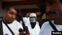 Vigilantes stand outside town hall after entering Nueva Italia, Mexico, Jan. 12, 2014.