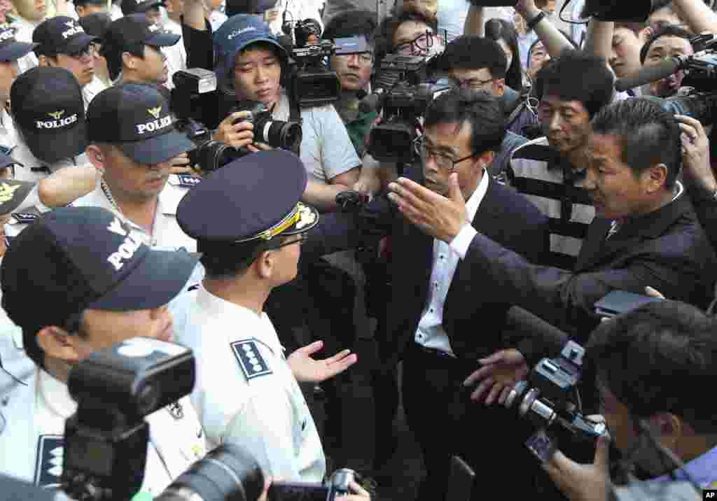 Para anggota keluarga penumpang kapal kapal feri Sewol yang tenggelam meminta pada polisi untuk bertemu awak kapal usai sidang pra-peradilan untuk mereka di Pengadilan Distrik Gwangju, Gwangju, Korea Selatan (10/6).&nbsp;(AP/Ahn Young-joon)