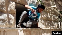 A Free Syrian Army fighter climbs through a hole in a wall in Bustan al-Basha district in Aleppo, Syria, May 19, 2014. 