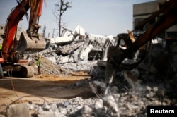 FILE - Palestinian workers clear the rubble of a school that witnesses said was destroyed by Israeli shelling in the east of Gaza City, Dec. 3, 2014.