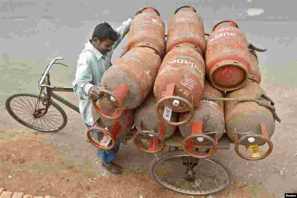 A worker loads Liquefied Petroleum Gas (LPG) cylinders onto his cycle-rickshaw in Kolkata, India.