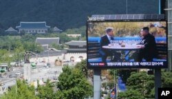 A TV screen shows a photo of South Korean President Moon Jae-in and North Korean leader Kim Jong UN, right, to advertise upcoming Seoul Defense Dialogue in Seoul, South Korea, Sept. 5, 2018. The sign read: "Peace on the Korea Peninsula."