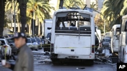 FILE - A man walks past the bus that exploded Tuesday in Tunis.